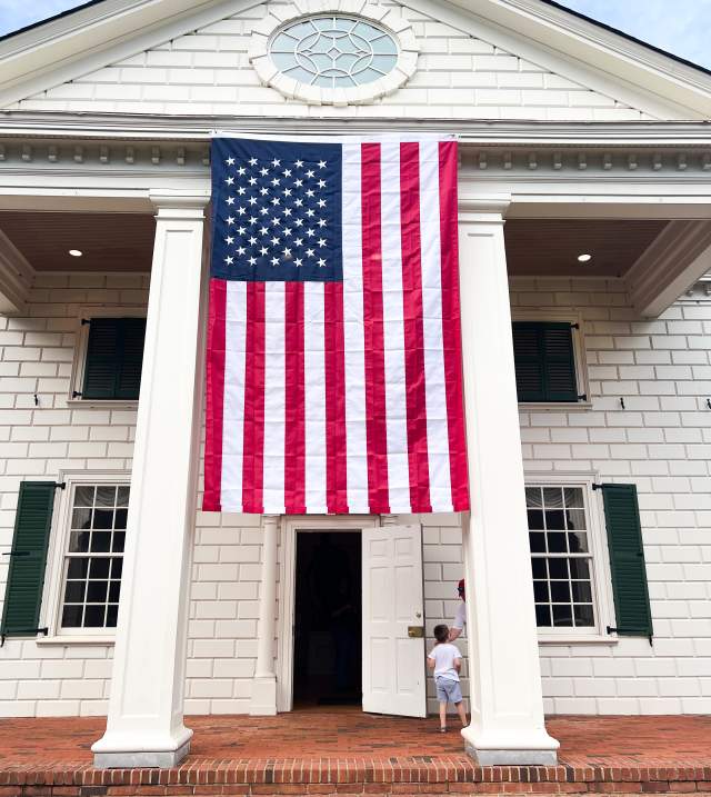 A young boy enters an exhibit at the American Village in Montevallo. An American flag hangs over the doorway.