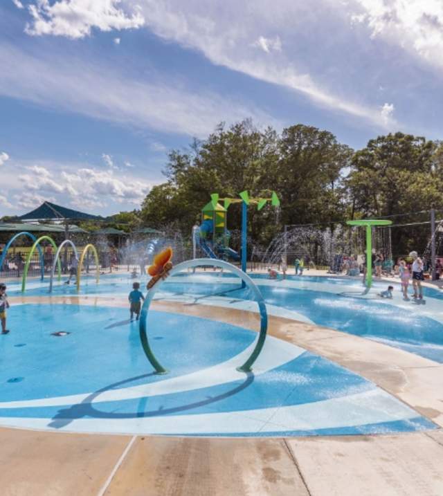 A concrete splash pad with overhead fountains, waterfalls, hoops, and other attractions!