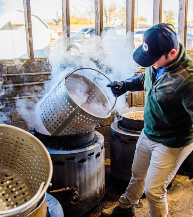 man grabbing large metal crawfish pot to place in boiling water