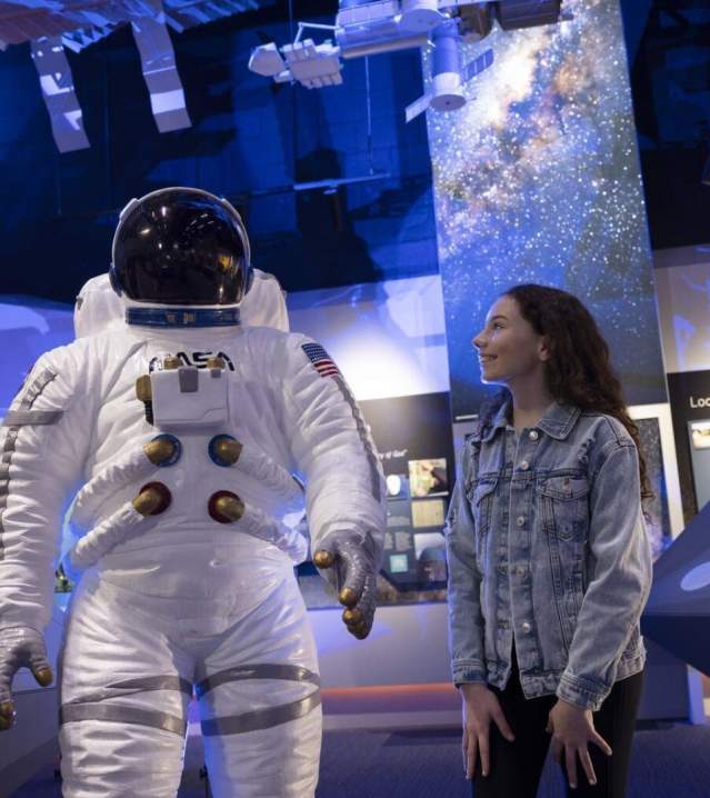 Girl standing beside a replica spacesuit at Armagh Observatory and Planetarium