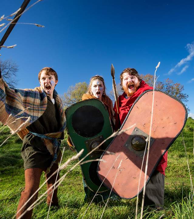 Group of three dressed up in medieval warrior costume at Navan Fort