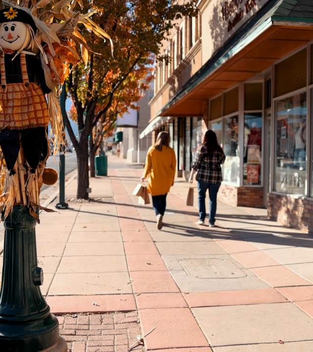 Two women walk down Main Street in Cedar City, Utah with shopping bags in hand