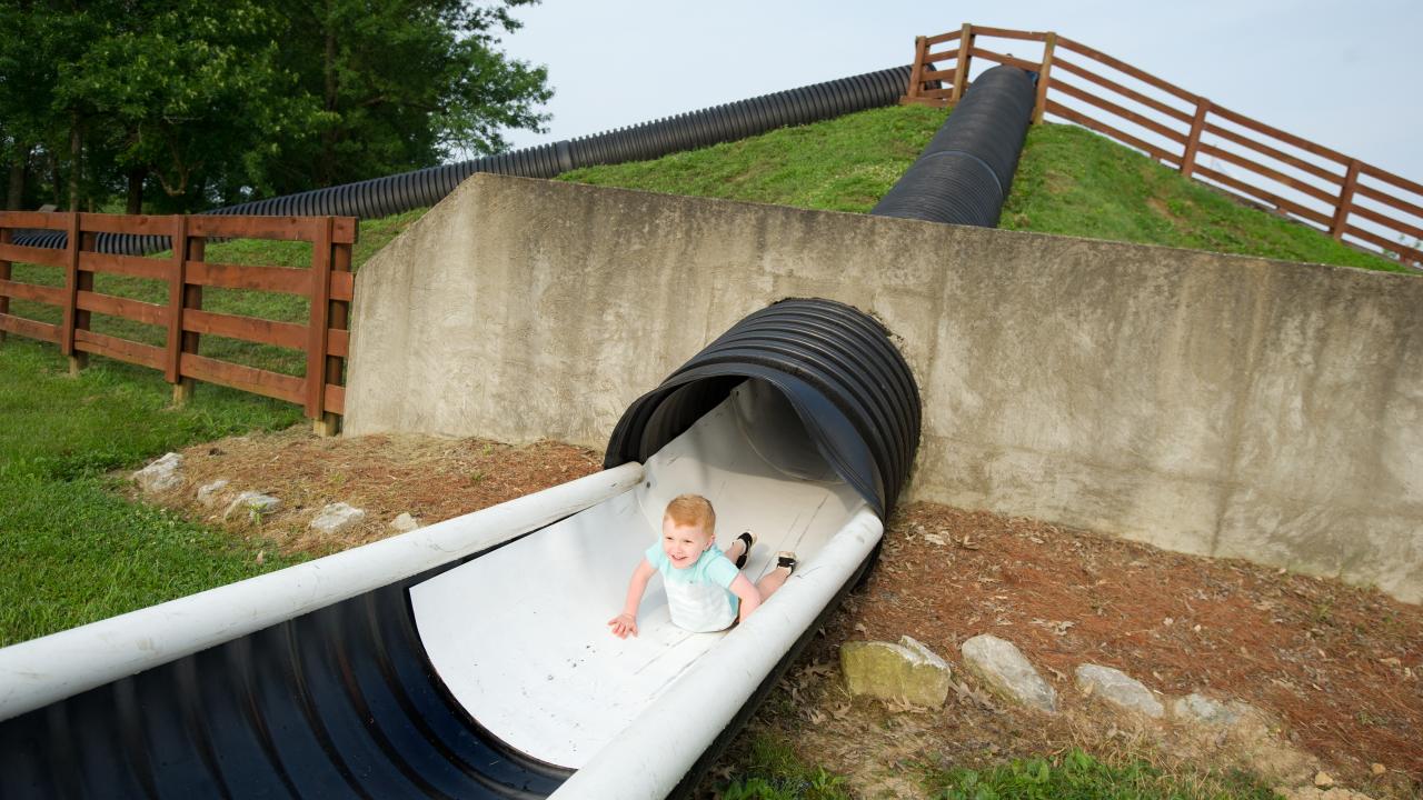 Young boy sliding down head first on a hill slide at Huber's Orchard & Winery