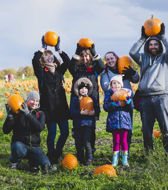 family with their pumpkin haul in the patch