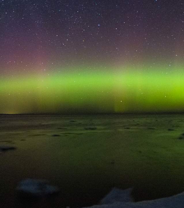 northern lights dance above a lake with floating ice