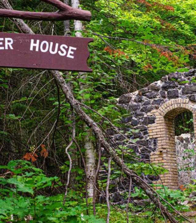 A sign reading: "Powder House" is visible in front of a ruined stone building surrounded by thick forest