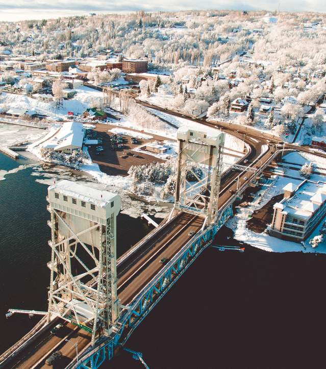 Aerial shot of the Portage Lake Lift Bridge and Hancock can be seen covered in snow.
