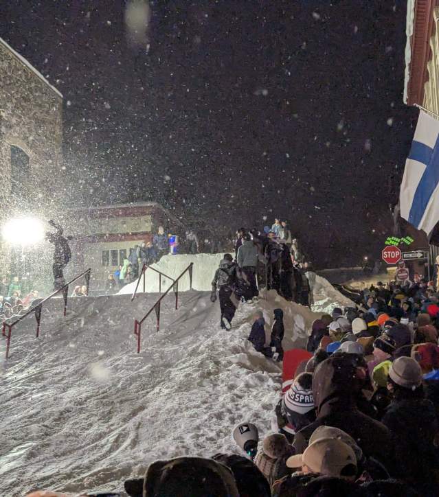 snowboarder hits a jump in view of a crowd