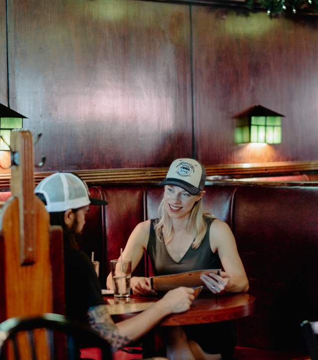A couple looks at a menu in a booth at a restaurant.