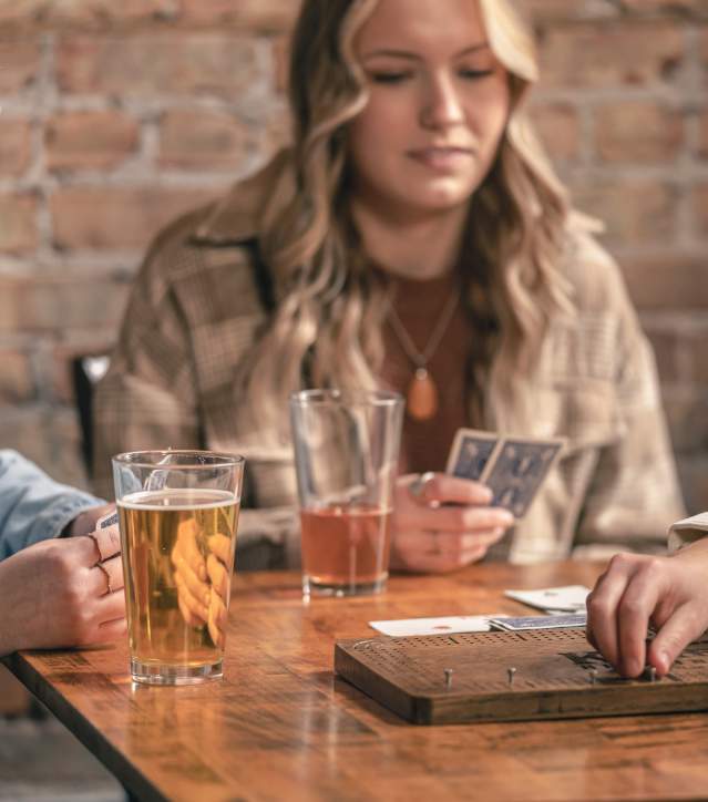Girls enjoy pints of local beer and play a game of cribbage at a local brewery.