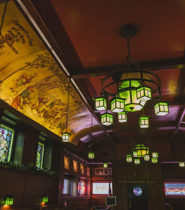 long dining hall with ceiling murals and stained glass chandeliers
