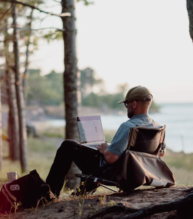 A man works on his laptop on the shores of Lake Superior.
