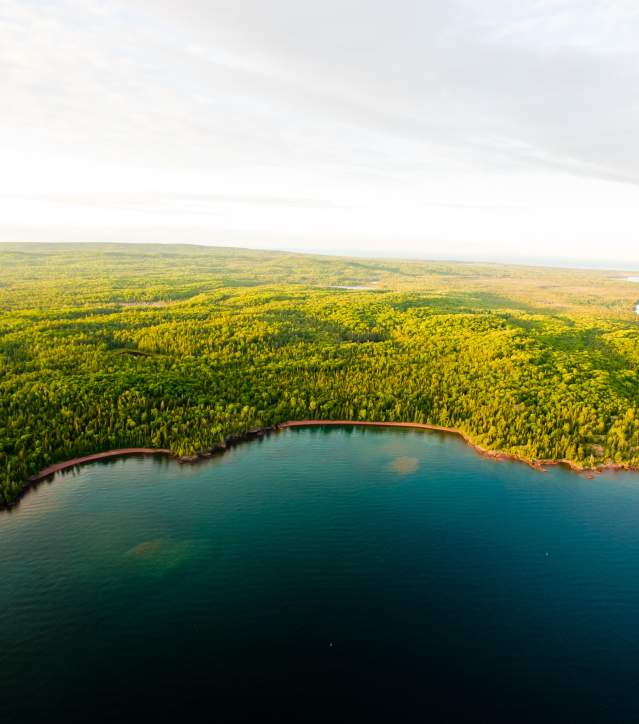 Aerial shot of green forests and Lake Superior shoreline.