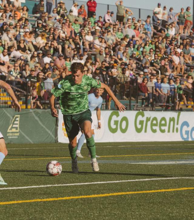 Vermont Green soccer player kicking a ball