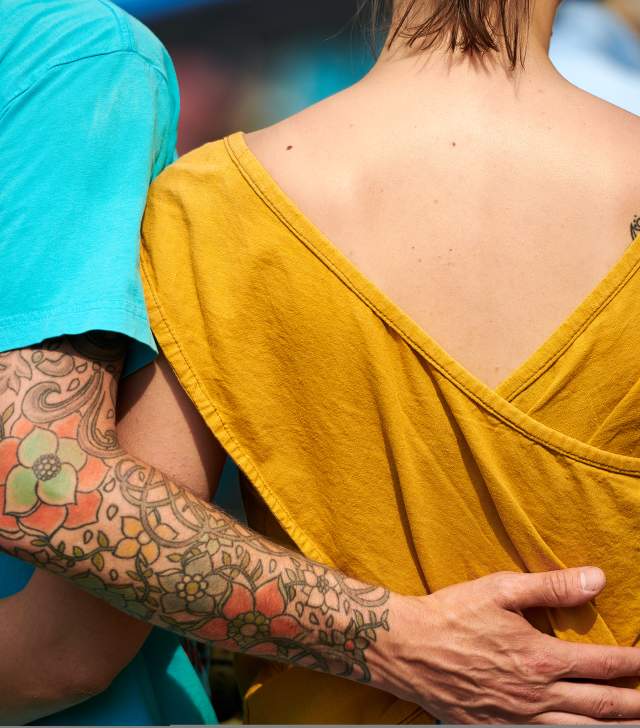 two people embrace with creative artwork aligned on their forearms