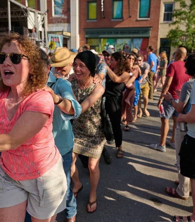woman in pink shirt having fun in a dancing conga line at Discover Jazz Festival in Burlington VT