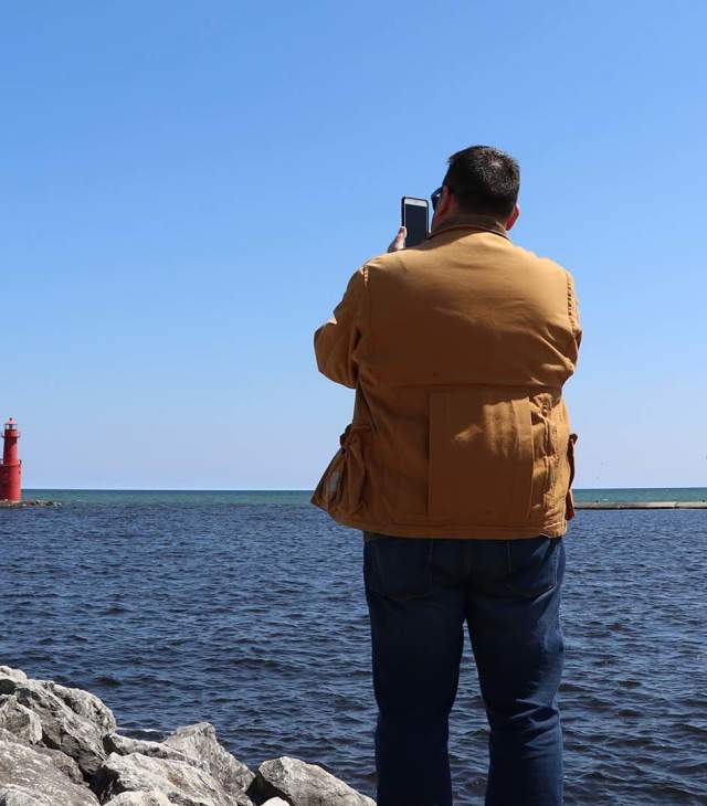 Man takes photo of lighthouse in Algoma on the shore of Lake Michigan