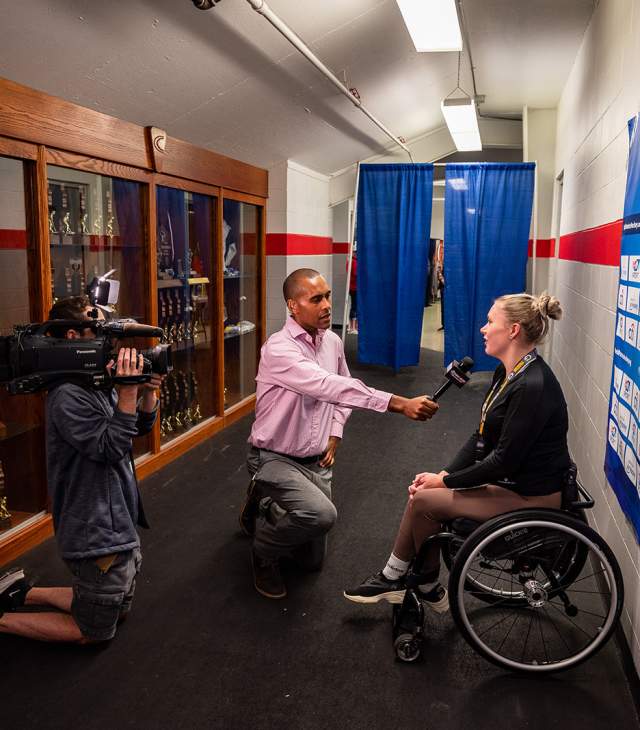 Media interviewing athlete at para ice hockey event.