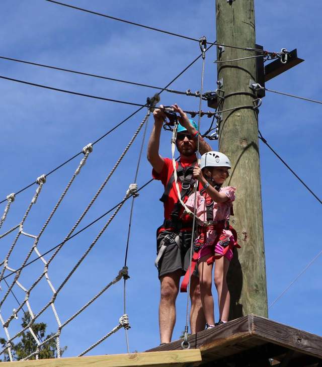 A guide straps in a child at the ropes course at the NEW Zoo adventure park
