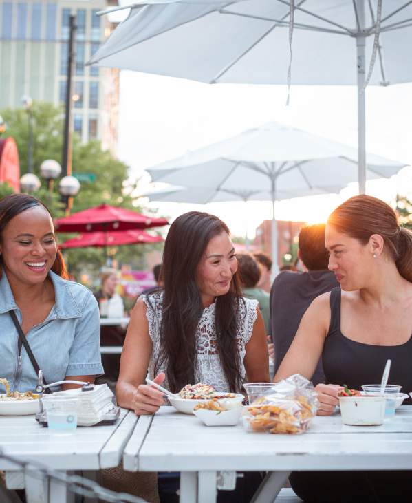 Three people eating outside at Fritas Batidos