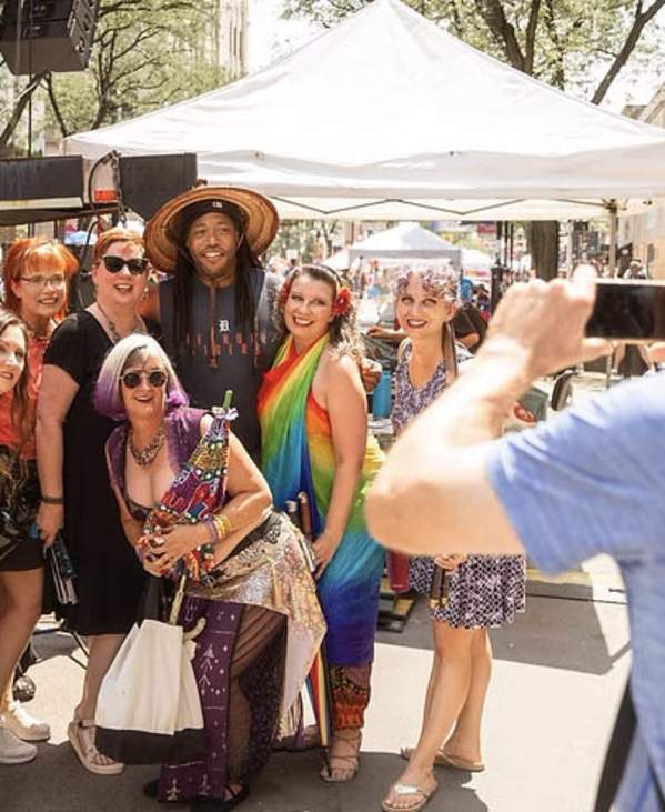 A group of people wearing colorful clothing getting a group photo taken at Ann Arbor Pride