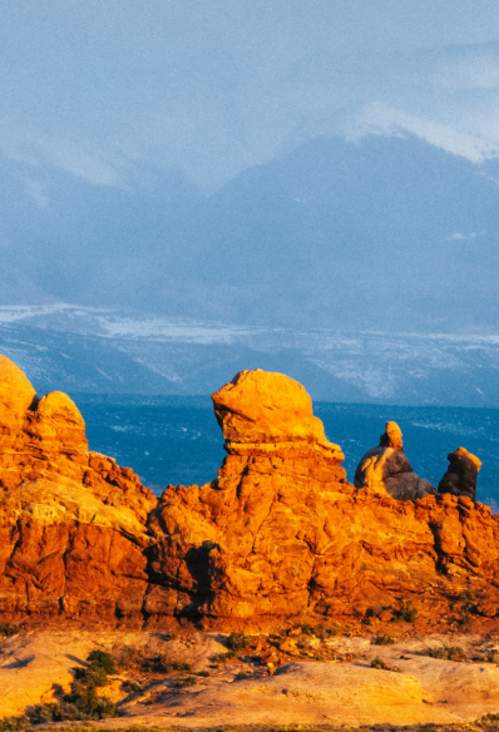 The red rocks of Turret Arch and the surrounding rock fins in The Windows Section of Arches National Park, framed against the snow-capped La Sal Mountains in Moab, Utah.