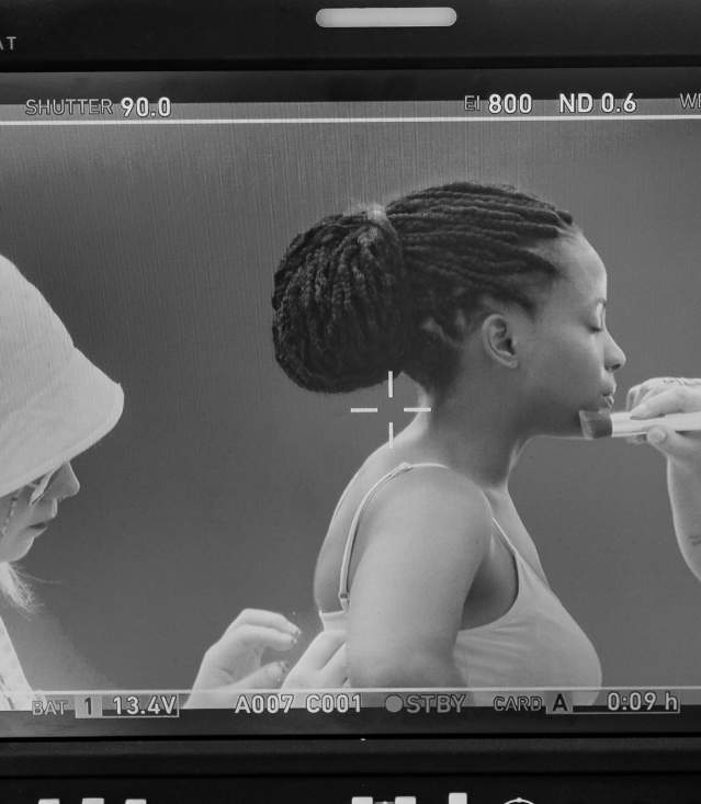 Beautiful young lady receiving makeup and costume touchups on camera.