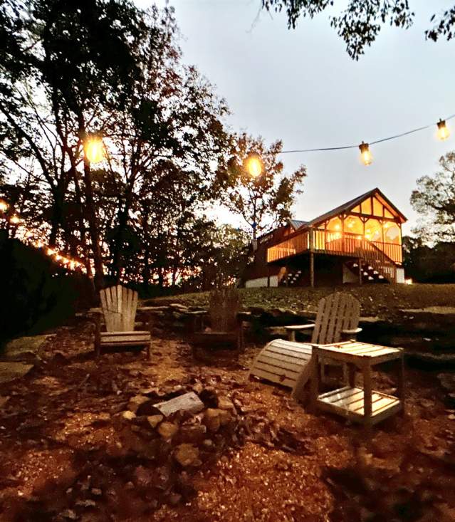 Fire Tower Camp cabin and chairs with string lights at dusk.