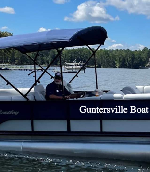 Pontoon boat on water on a sunny day with gentleman driving.