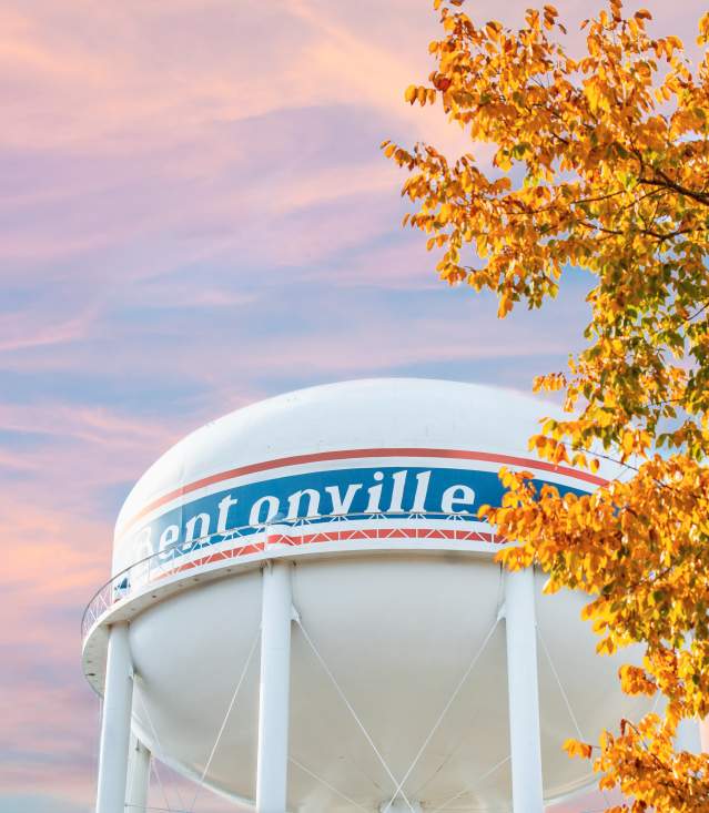 Image of the Bentonville water tower with fall leaves and cotton candy colored sky