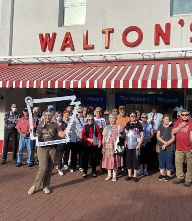 A group of people standing in front of a large brick building with the sign "WALTON'S 5-10".
