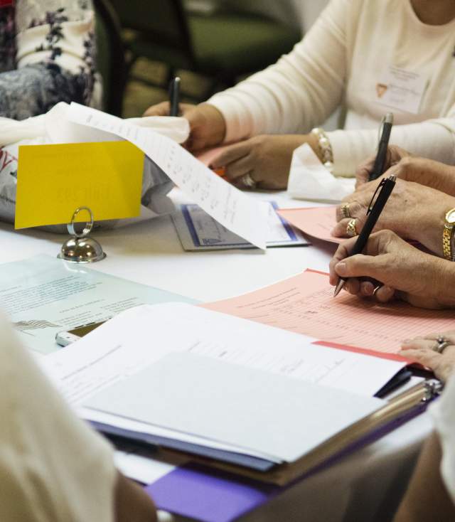 Image of a group of people taking notes at a meeting