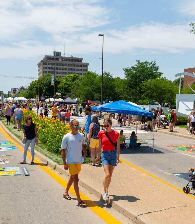 people walking through a sidewalk chalk festival