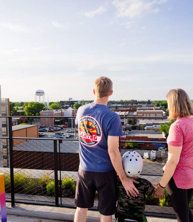 Family overlooking Bentonville's town center from a rooftop, showcasing urban landscape and community vibe.
