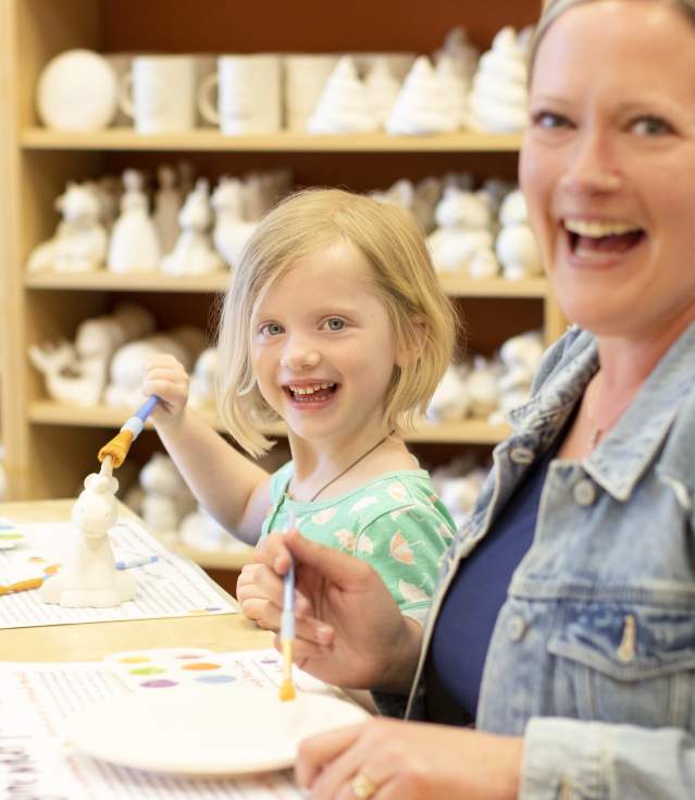 A child and woman pose smiling preparing to paint pottery at Crock a Doodle Bentonville