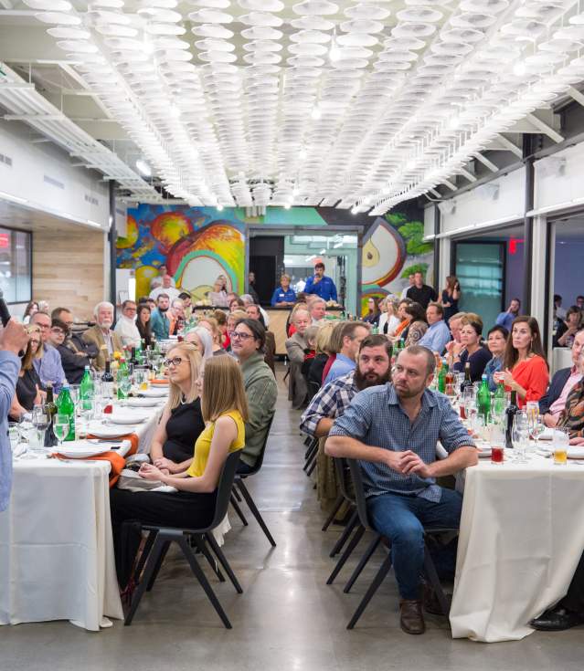 A group of people sitting at tables listening to a speaker at Brightwater: A Center for the Study of Food