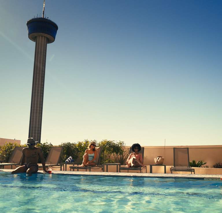 People enjoying pool with Tower of the Americas in distance