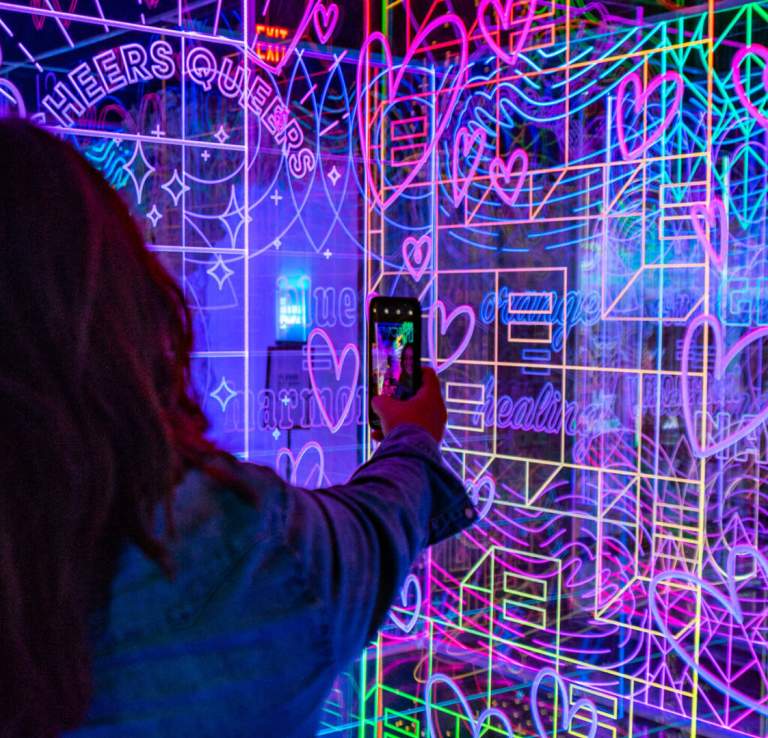 Woman taking photo with her phone of multicolored wall