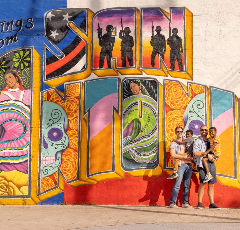 Family posing in front of Greets from San Antonio Mural