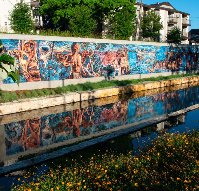 Public art along wall in front of creek