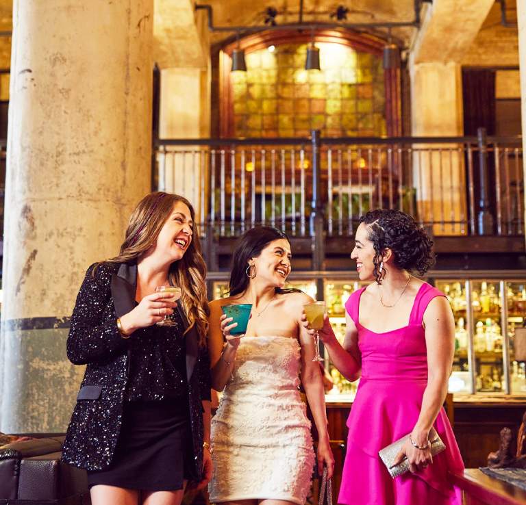 Three girls enjoying drinks in beautiful room with two large pillars