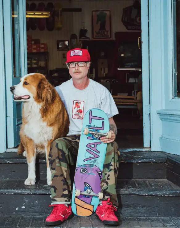 man sitting with a dog and a skateboard