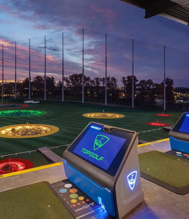 Golf bays at Topgolf Woodbury with sun setting in the background