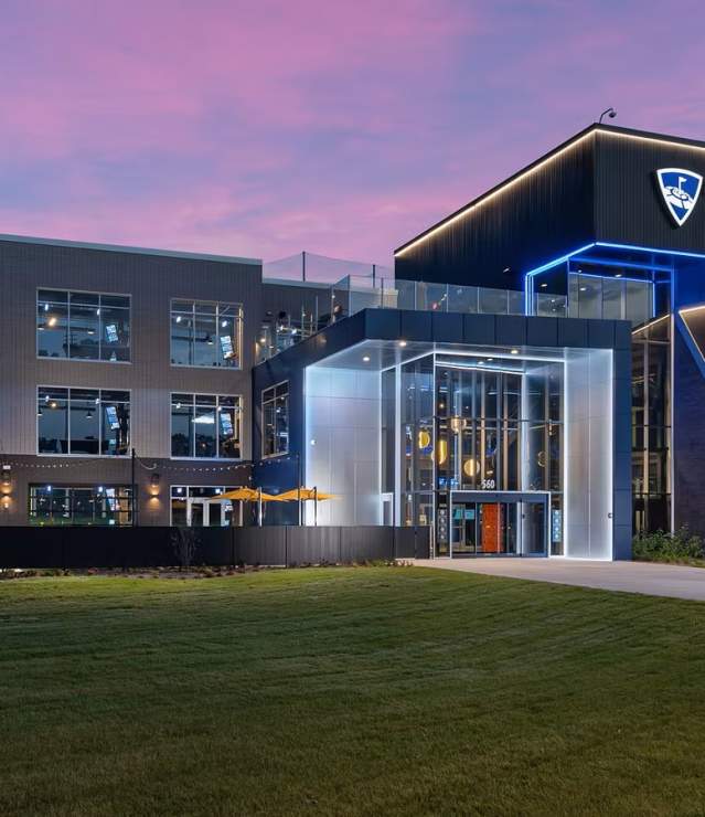 Topgolf Woodbury at sunrise with the lights on the building.