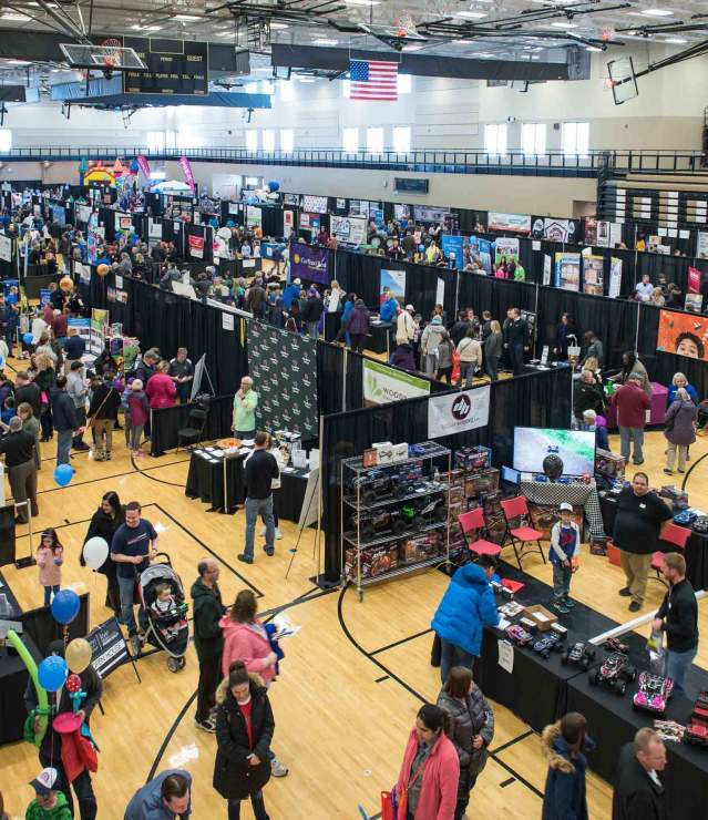 Large community expo taking place in recreational facility showcasing local businesses at exhibit booths