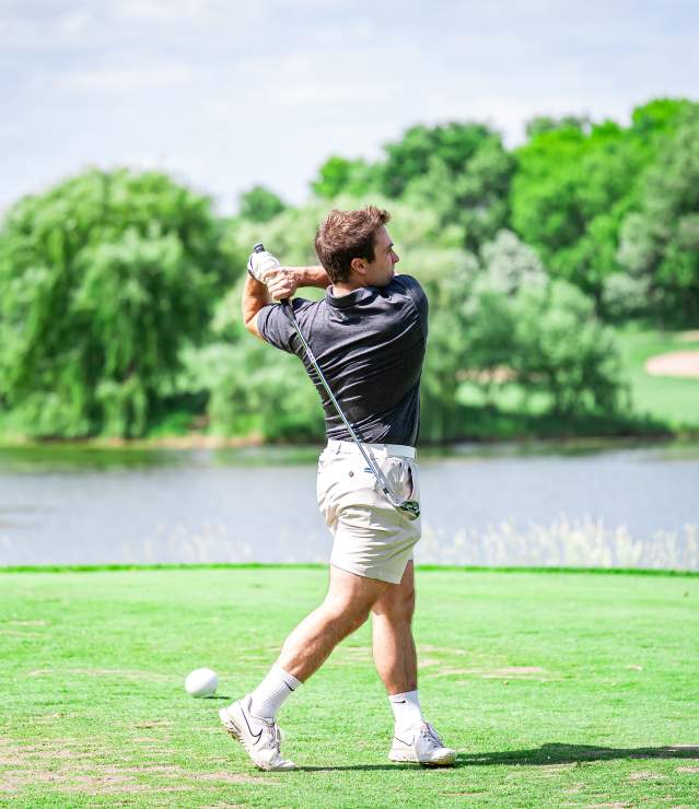 Golfer teeing off at Eagle Valley Golf Course with water feature in the background