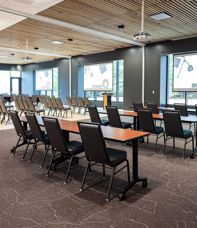 Meeting space shown with tables and chairs in Woodlands Room meeting space at Woodbury Central Park.