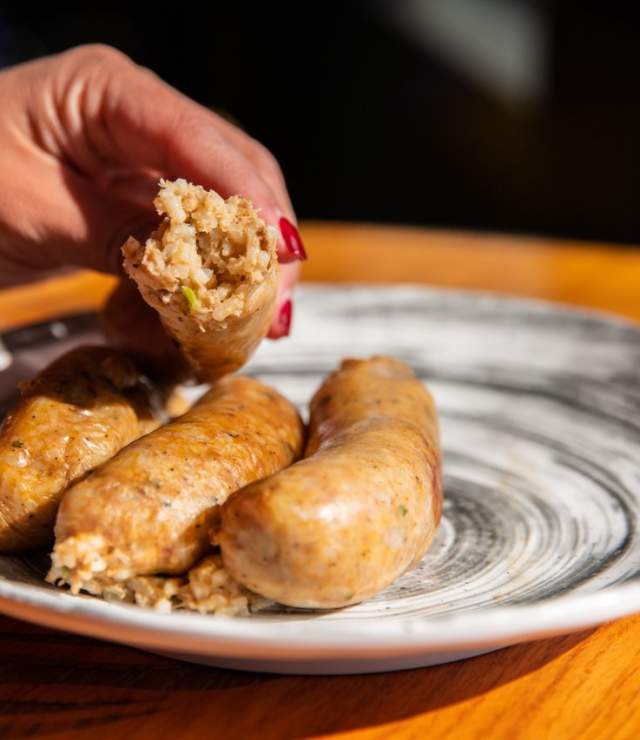 three links of boudin one held in hand