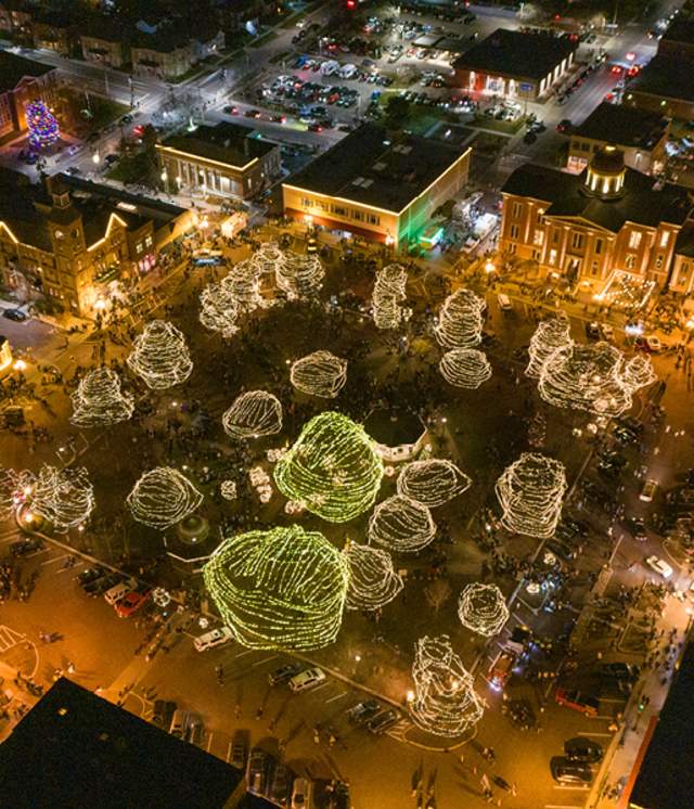 aerial view of the Woodstock Square at the holidays, with white lights covering trees and buildings.