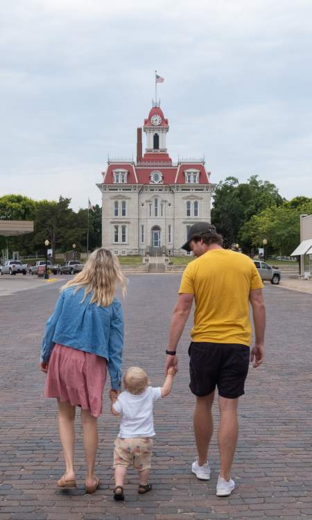 A family walks hand in hand on a brick street toward the Chase County Courthouse
